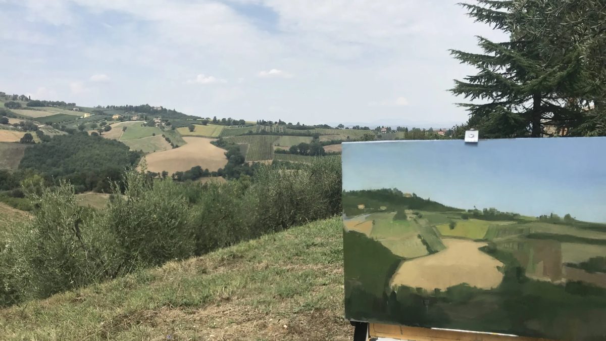 Work in progress picture showing landscape painting in front of tuscan hills